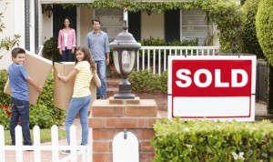 people with boxes in front of a house with a sold sign
